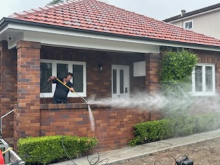 Pressure cleaning in progress on the verandah of a red-brick house
